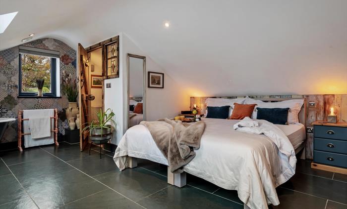 first floor bedroom offering superking or twin beds, bedside cupboards, en-suite with basin, w.c. and chest of drawers, roll top bath, smart TV, dress